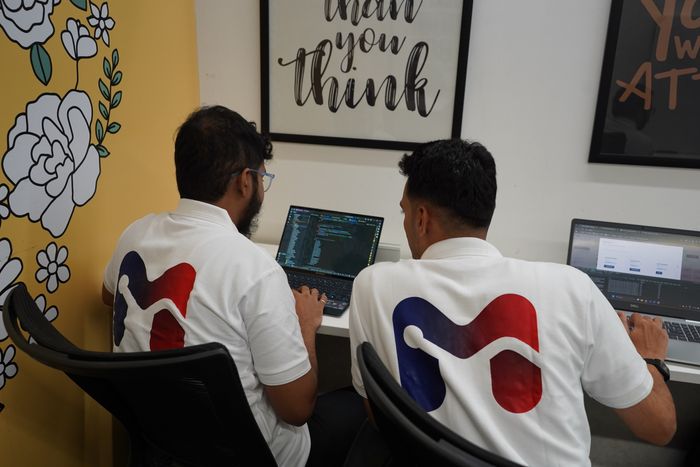 Two Alliance Corporation developers reviewing work together on a laptop