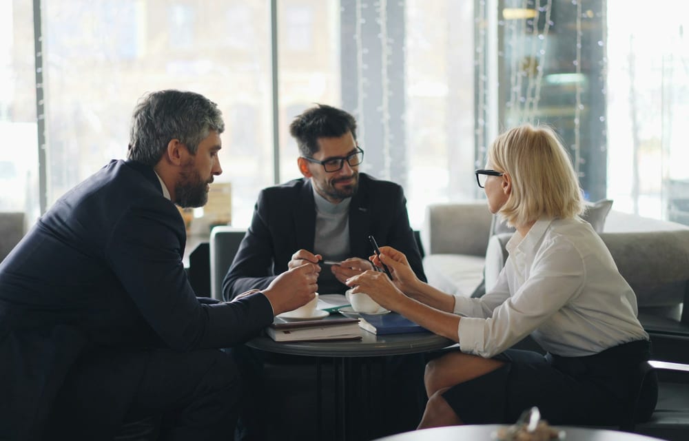 Three consultants reviewing delivery plans around a table